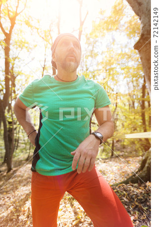 Portrait of a bearded man in age stands near a taut slackline in an autumn forest Portrait of a bearded man in age stands near a taut slackline in an autumn forest 72142149