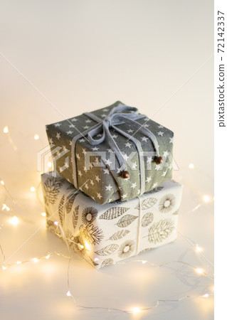 Waste-free Christmas, eco-friendly gift wrapping in fabrics with natural composition, eco-friendly Christmas concept, minimalism. Christmas New Year concept. Garland and holiday lights Waste-free Christmas, eco-friendly gift wrapping in fabrics with natural composition, eco-friendly Christmas concept, minimalism. Christmas New Year concept. Garland and holiday lights 72142337