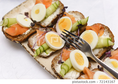 bruschetta with cheese, cucumber, salmon and boiled egg on a plate, 72143167