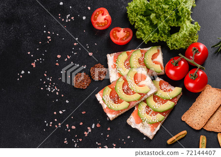 Delicious fresh sandwich with red fish, butter, bread and avocado Delicious fresh sandwich with red fish, butter, bread and avocado 72144407