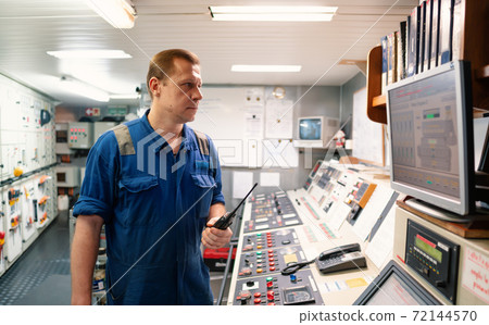 Marine Engineer working on radio communication at Engine Control room ECR Marine Engineer working on radio communication at Engine Control room ECR 72144570
