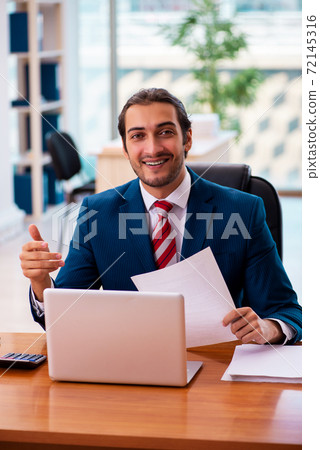 Young handsome employee working in the office Young handsome employee working in the office 72145316
