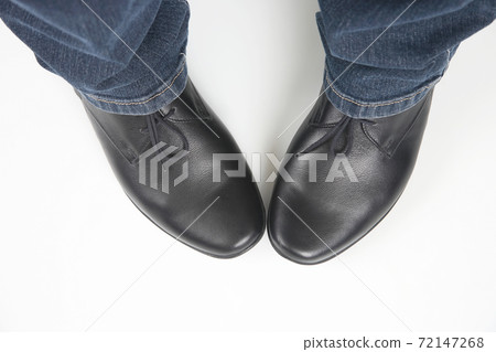 Men's legs in jeans and black classic shoes on white background 72147268