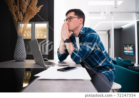 Portrait of a thoughtful young businessman working remotely from home using laptop 72147354