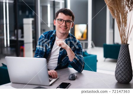 Portrait of handsome young man working remotely at home and smiling happily at camera Portrait of handsome young man working remotely at home and smiling happily at camera 72147363