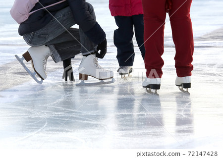 the feet of the people skating at the rink. 72147428