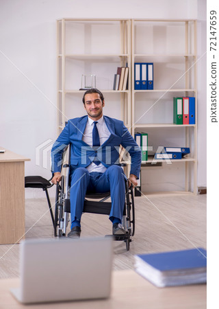 Young male employee in wheel-chair working in the office Young male employee in wheel-chair working in the office 72147659