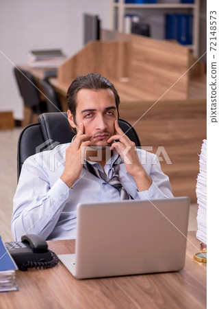 Young male employee unhappy with excessive work in the office 72148573