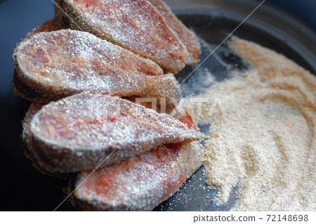 Cooking fish dishes. Raw pieces of pink salmon or chum salmon in breadcrumbs are on the plate. Cooking fish dishes. Raw pieces of pink salmon or chum salmon in breadcrumbs are on the plate. 72148698