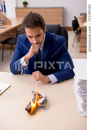 Young male employee burning papers in the office Young male employee burning papers in the office 72149395