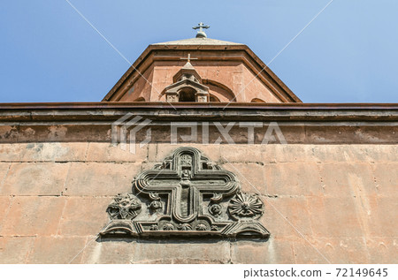 Figured cross with the faces of saints over the entrance to the "Zoravar" Church of the most Holy Virgin with a miniature Church on the roof in Yerevan Figured cross with the faces of saints over the entrance to the "Zoravar" Church of the most Holy Virgin with a miniature Church on the roof in Yerevan 72149645