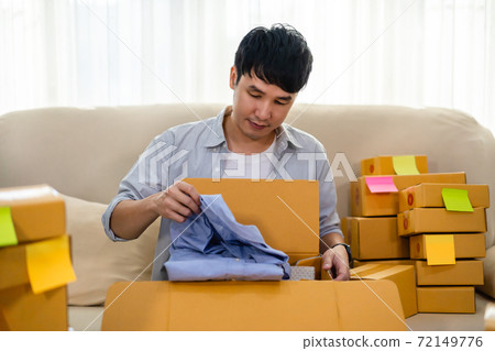 happy man open cardboard parcel box in living room at home, purchase on online store happy man open cardboard parcel box in living room at home, purchase on online store 72149776