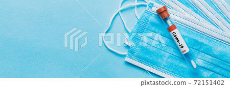One single glass test tube containing a Corona virus test swab sitting on top of some blue surgical masks One single glass test tube containing a Corona virus test swab sitting on top of some blue surgical masks 72151402