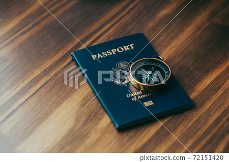 One gold compass on top of a blue American passport 72151420