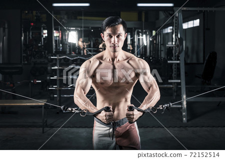 Strong fitness man doing arm workout with cable machine in the gym Strong fitness man doing arm workout with cable machine in the gym 72152514