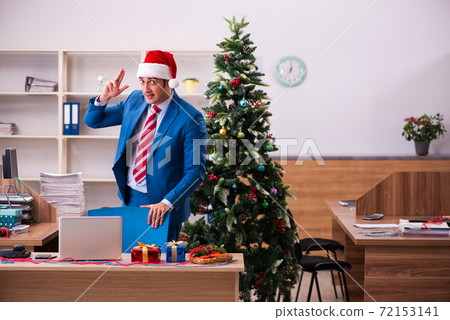 Young male employee celebrating Christmas at workplace Young male employee celebrating Christmas at workplace 72153141