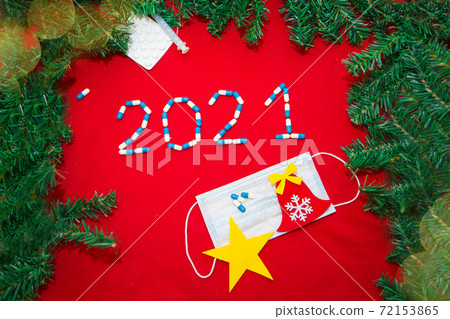 coronavirus, ncov-19 and the New year. Holiday in self-isolation, hospital. Christmas decorations and medical devices mask, pills and syringe. Copy space on a red background 72153865