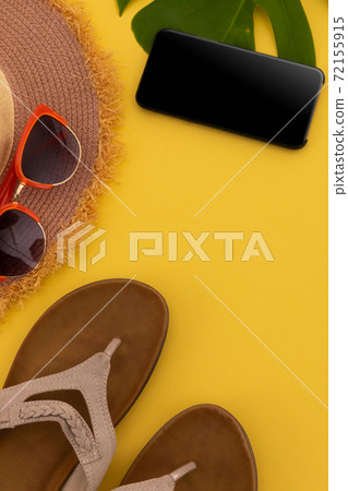 Sunglasses, flip flops, sunhat and smartphone on yellow background Sunglasses, flip flops, sunhat and smartphone on yellow background 72155915