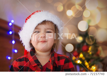 a child in red clothes is sitting waiting for the new year. the concept of celebrating Christmas at midnight. holiday costume a child in red clothes is sitting waiting for the new year. the concept of celebrating Christmas at midnight. holiday costume 72157740