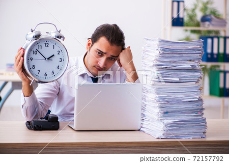 Young male employee unhappy with excessive work in time manageme Young male employee unhappy with excessive work in time manageme 72157792