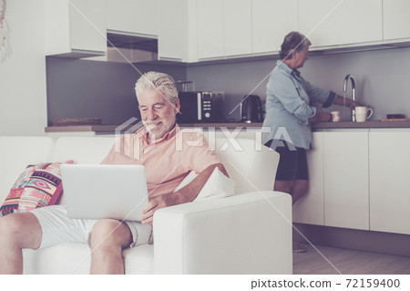 Stayhome and lockdown coronavirus old people concept - senior caucasian couple inside house in the kitchen cooking and use modern connected laptop computer - real life together Stayhome and lockdown coronavirus old people concept - senior caucasian couple inside house in the kitchen cooking and use modern connected laptop computer - real life together 72159400
