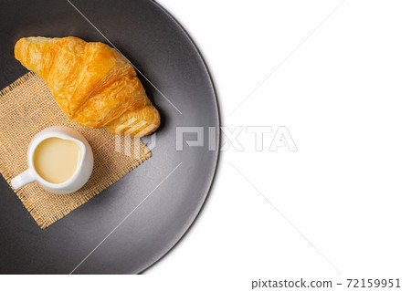 Croissant on black plate with sweetened condensed milk and sackcloth Croissant on black plate with sweetened condensed milk and sackcloth 72159951