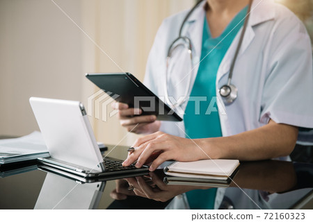 Male doctor working on desk with laptop computer and paperwork in the office. Medical and doctor concept. Male doctor working on desk with laptop computer and paperwork in the office. Medical and doctor concept. 72160323