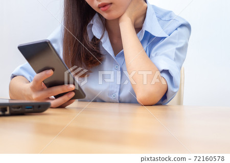 Asian woman using hand to massage her neck. Crouching of head, taking pressure on the spine, neck fatigue, muscle pain due to prolonged play, or incorrect posture when using smartphone. 72160578