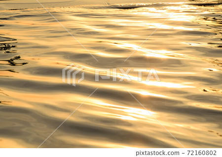 The light of the sun on the water ripple surface golden color. For the texture and the background. 72160802