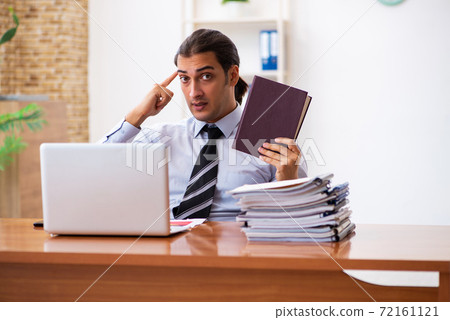 Young male student employee reading book at workplace Young male student employee reading book at workplace 72161121