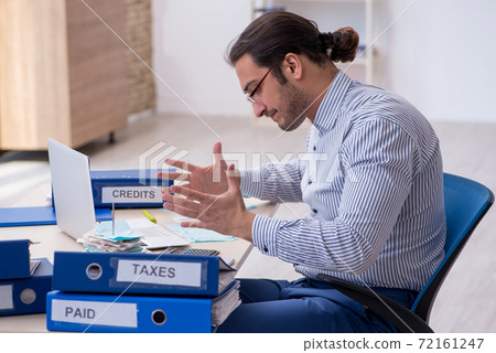 Young male bookkeeper calculating tax payments in the office Young male bookkeeper calculating tax payments in the office 72161247