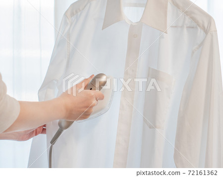 Ironing a shirt with a clothes steamer. Hands to steam iron. 72161362