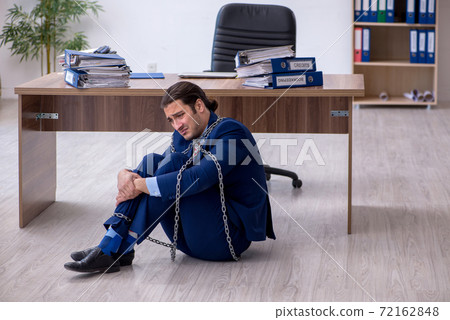 Chained male employee unhappy with excessive work in the office Chained male employee unhappy with excessive work in the office 72162848