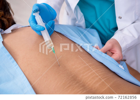 Young back injured man visiting female doctor chiropractor 72162856