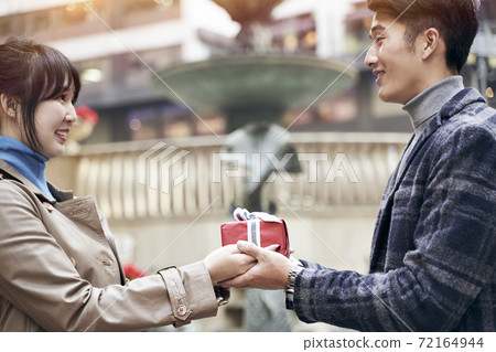 young asian woman ceceiving a christmas or birthday present from husband or boyfriend 72164944