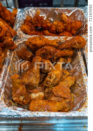 Delicious fried chicken drumsticks in aluminum tray at food market 72165092
