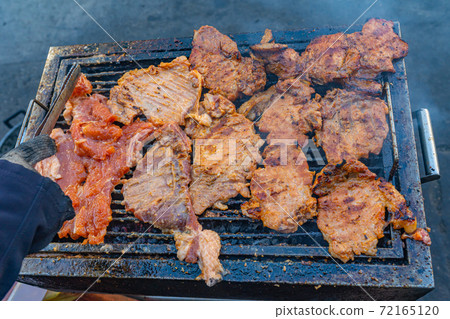 Grilling pork chop on coal pan at street food vendor Grilling pork chop on coal pan at street food vendor 72165120