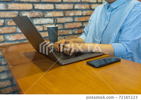 Asian businesswoman typing laptop next to smartphone on wooden table Asian businesswoman typing laptop next to smartphone on wooden table 72165123