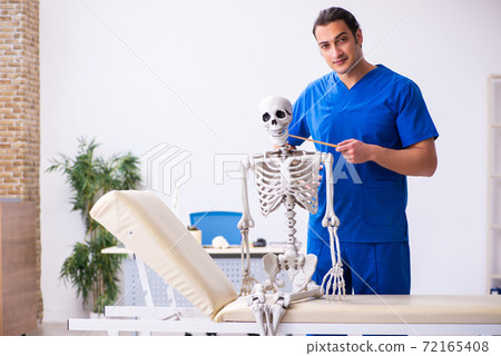 Young male doctor lecturer demonstrating skeleton Young male doctor lecturer demonstrating skeleton 72165408