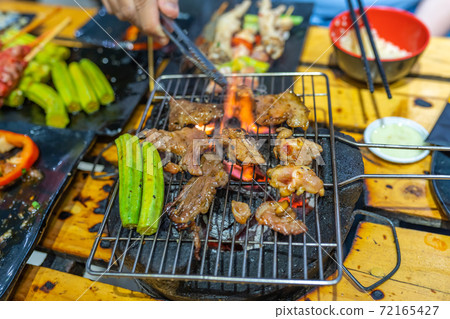 Barbecue meat and lady finger vegetables on flaming charcoal stove 72165427