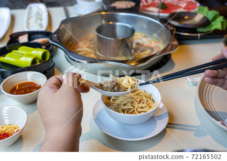Rear view of woman hands eating hotpot Rear view of woman hands eating hotpot 72165502