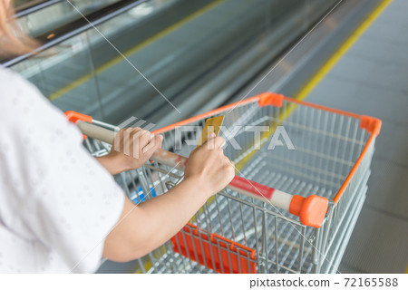 Woman hand pushing shopping carts to escalator 72165588