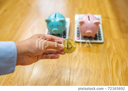 Businesswoman hand holding bitcoin with piggybank and calculator background Businesswoman hand holding bitcoin with piggybank and calculator background 72165692