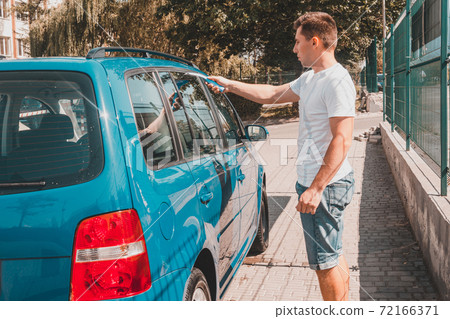 cleaning the car glass, a man wipes excess water from the glass in the car. cleaning the car glass, a man wipes excess water from the glass in the car. 72166371