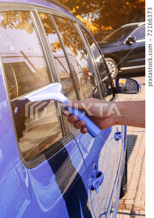 cleaning the car glass, a man wipes excess water from the glass in the car. cleaning the car glass, a man wipes excess water from the glass in the car. 72166373