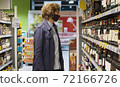 Handsome man choosing wine in the supermarket 72166726