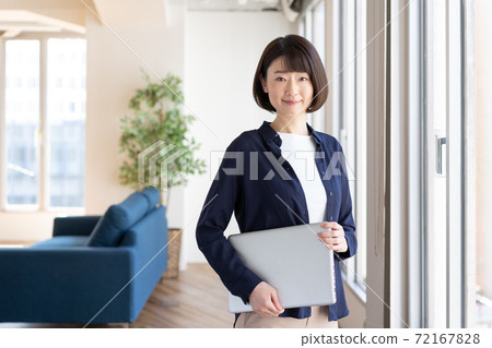 一個女人站在她手中的筆記本電腦 72167828