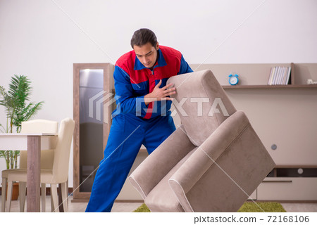 Young male contractor repairing arm-chair indoors 72168106