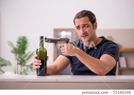 Young male alcoholic committing suicide at home Young male alcoholic committing suicide at home 72168198