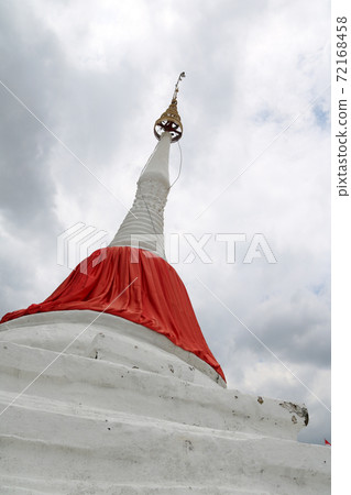 white leaning pagoda has a red cloth tied at the top beside Chao Phraya river at Koh kret 72168458